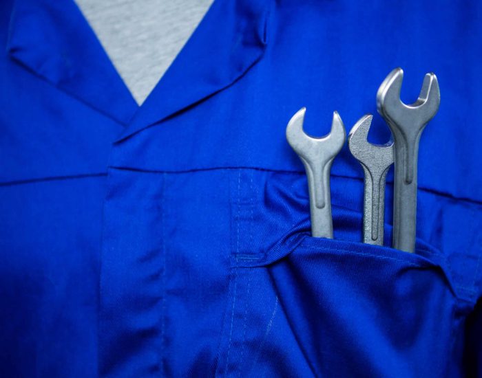 Mid section of mechanic with spanners in pockets at repair garage